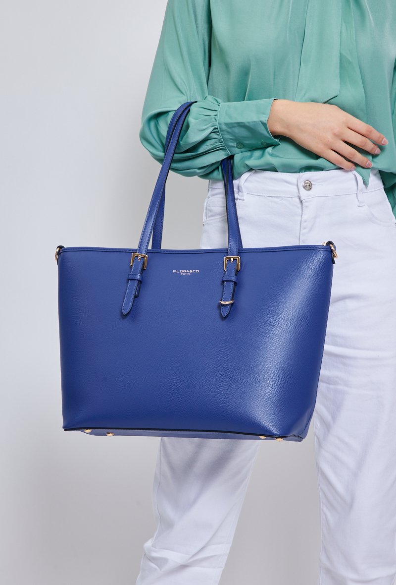 Vue de face du sac à main numéro 1808 bleu bic porté au bras de la mannequin de trois quart.