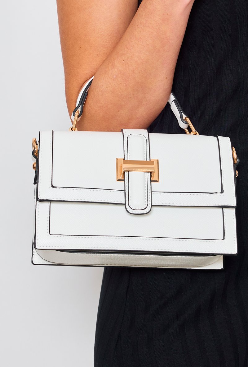 Vue de face du sac à main à bandoulière et rabat avec accroche métallisée blanc numéro 3680 au bras de la mannequin