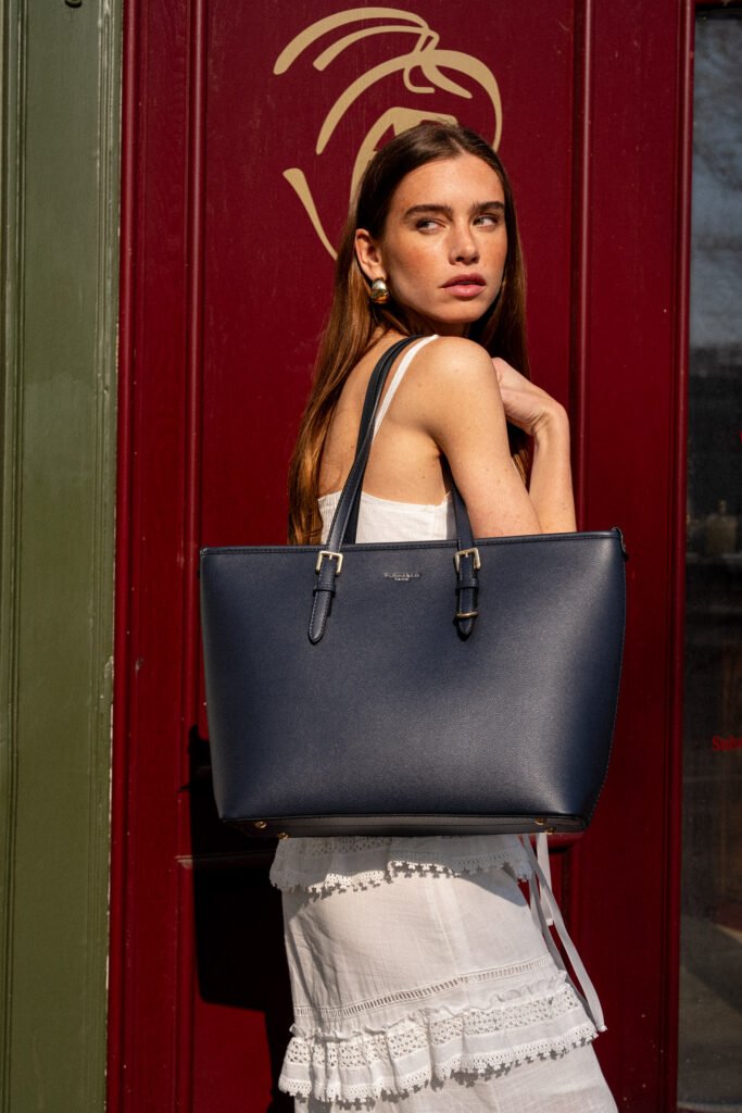 Femme qui pose avec un sac sur l'épaule devant une porte rouge